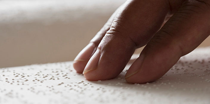 une main aide à la lecture, une facture en braille