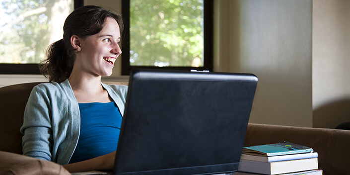 Femme utilisant un ordinateur avec l'offre solidaire Coup de Pouce Internet